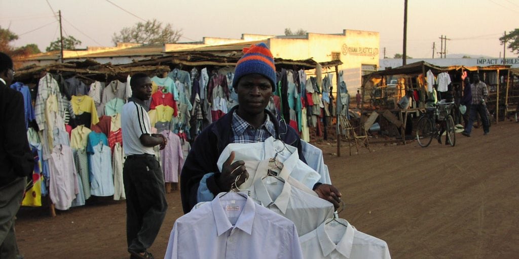 Malawian Man holding shirts at an outdoor market