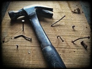 Hammer with nails on a rough hewn wooden board