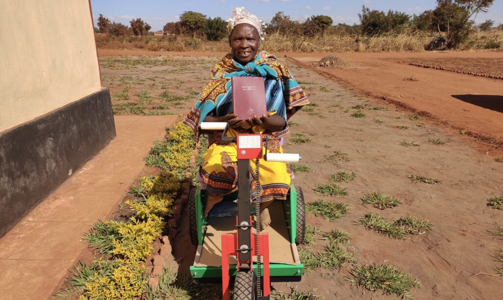 Leniya on her mobility unit holding a bible