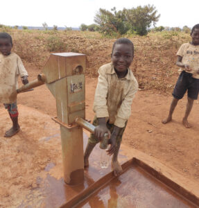 A boy pumping water from a well